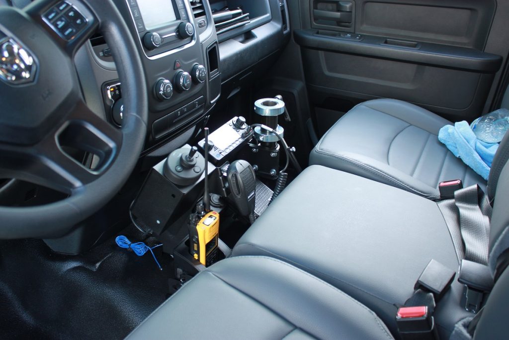 View of a modified truck interior with specialized controls and equipment installed between the driver and passenger seats.